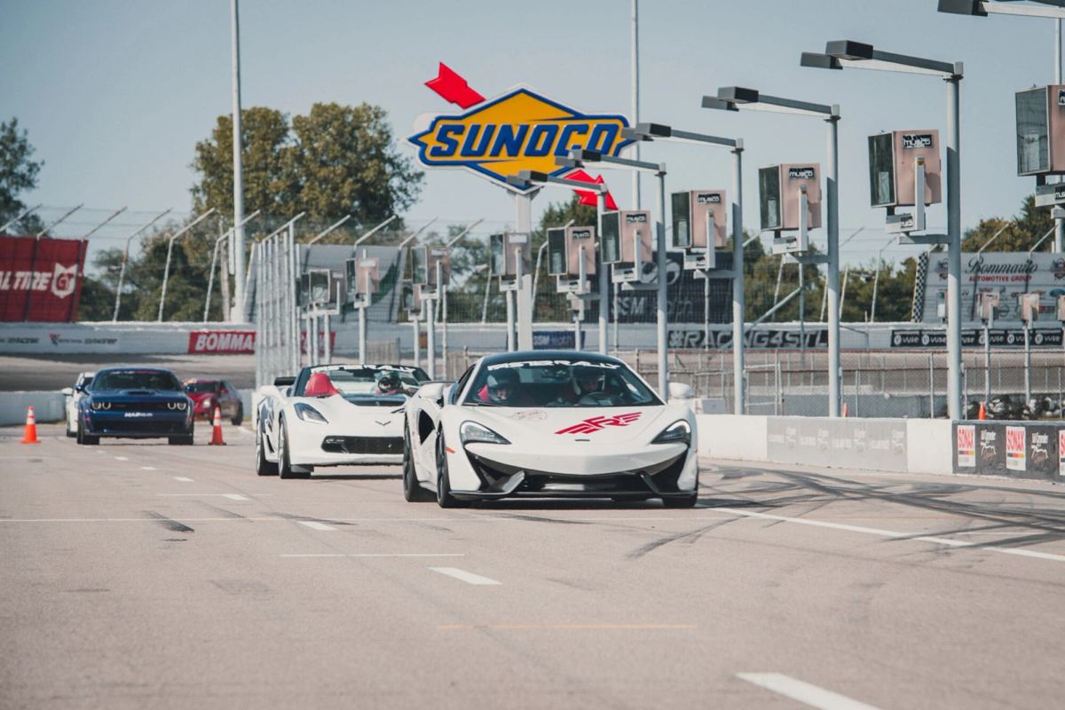 Supercars lined up on a race track at a Faster Rally event
