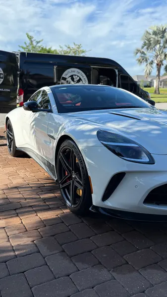 White Aston Martin Vantage with the black Outlaw Detailing mobile van behind it