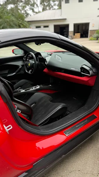 Clean black and red interior of a Ferrari 296 with the door open