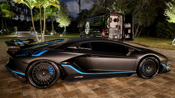 Black Lamborghini supercar on a paver driveway at night