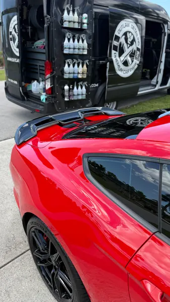 Outlaw Detailing mobile van with product shelves open beside a red Mustang, ceramic coating client in Sarasota