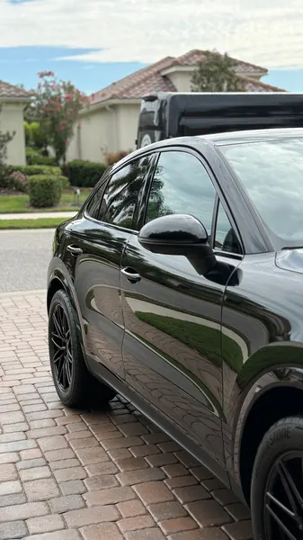 Black Porsche Cayenne Coupe side view reflecting the paver driveway